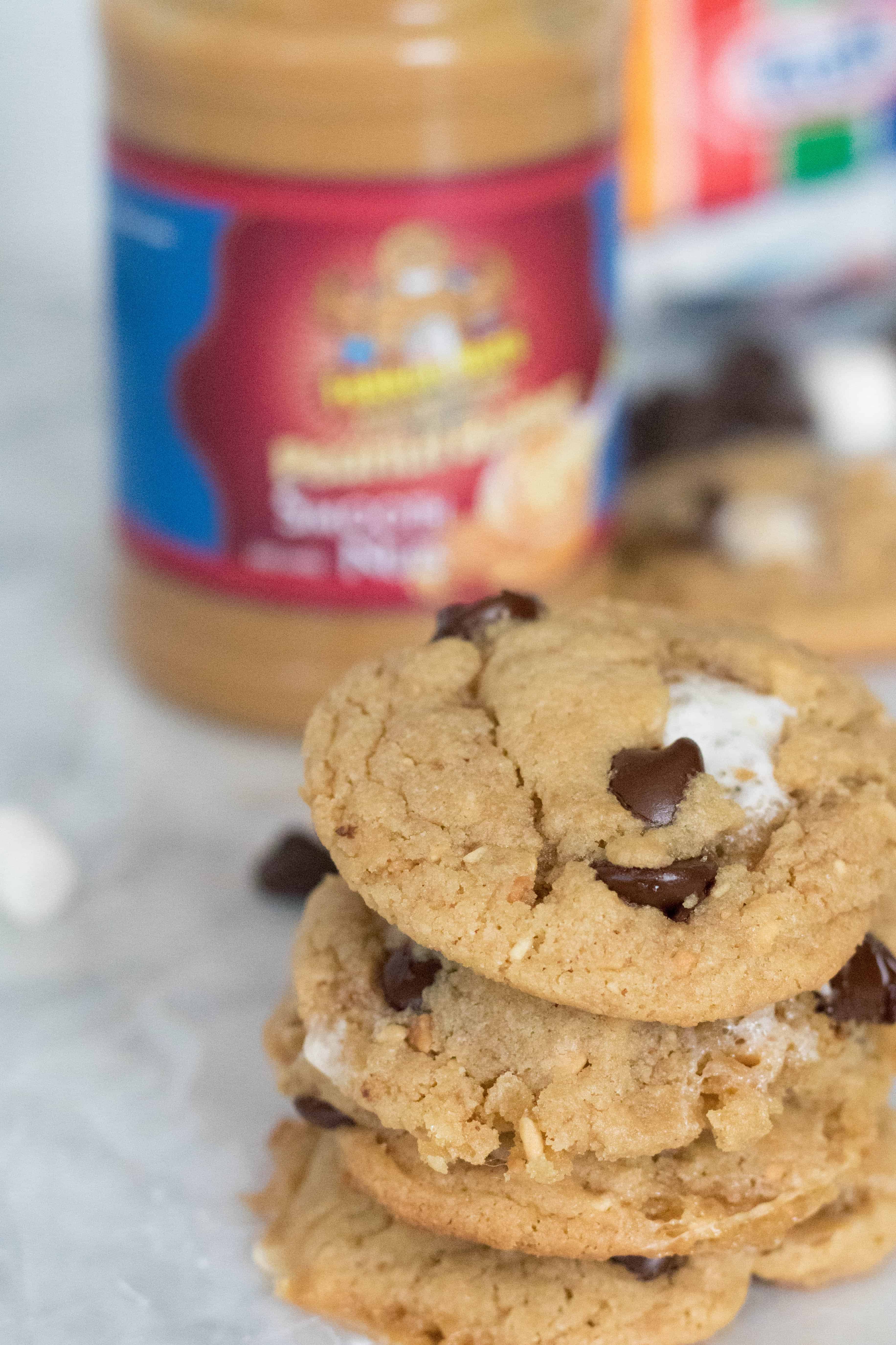 Un empilement de biscuits au beurre d’arachide et S’mores devant un pot de beurre de cacahuète Fokkennut