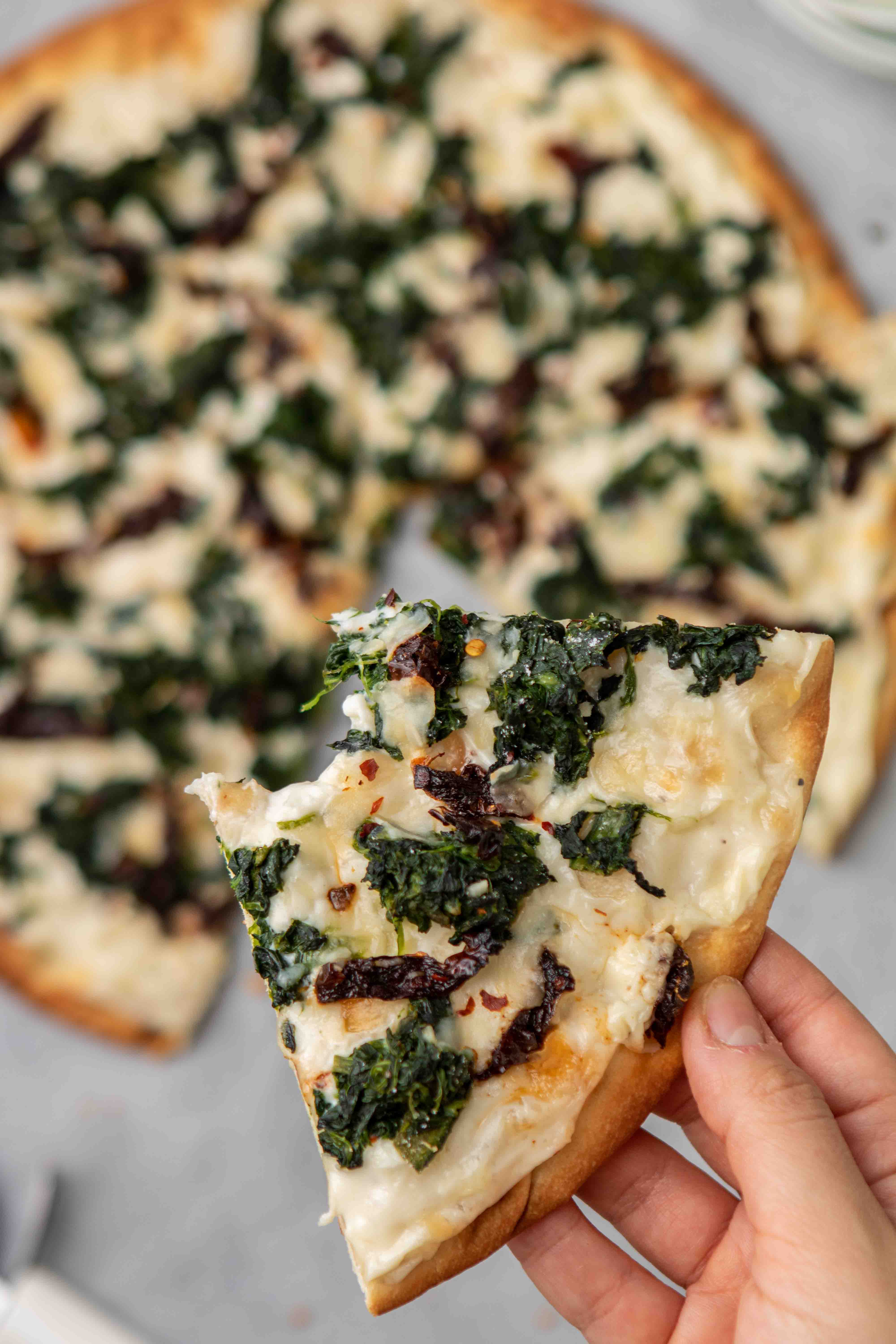 Gros plan d’une tranche de pizza aux épinards avec sauce blanche