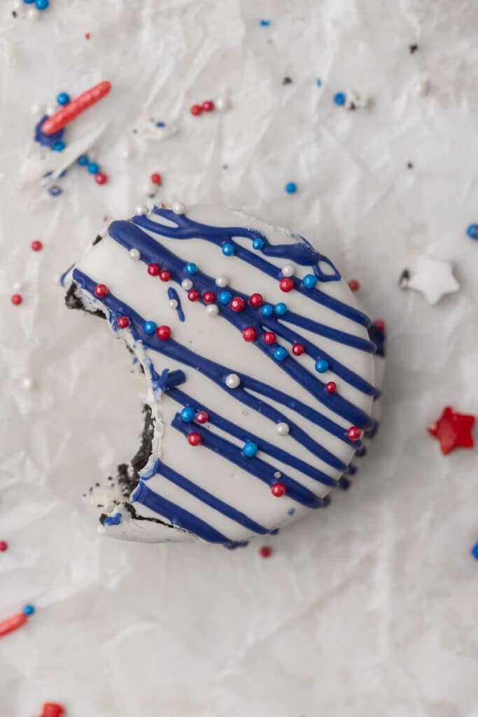 Oreo rouge, blanc et bleu enrobé de chocolat avec une bouchée prise dedans