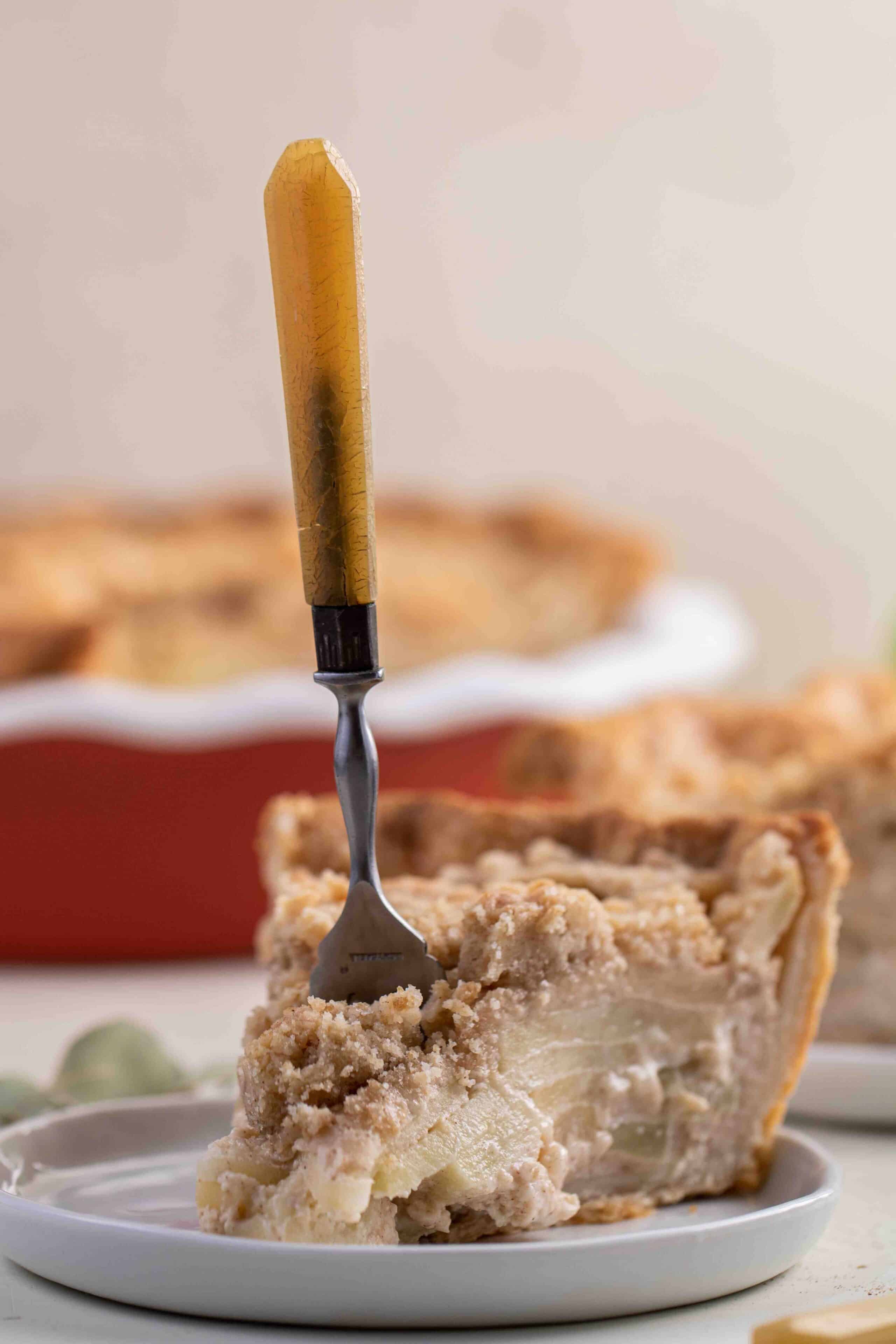 Tranche de tarte aux pommes avec une fourchette enfoncée au centre