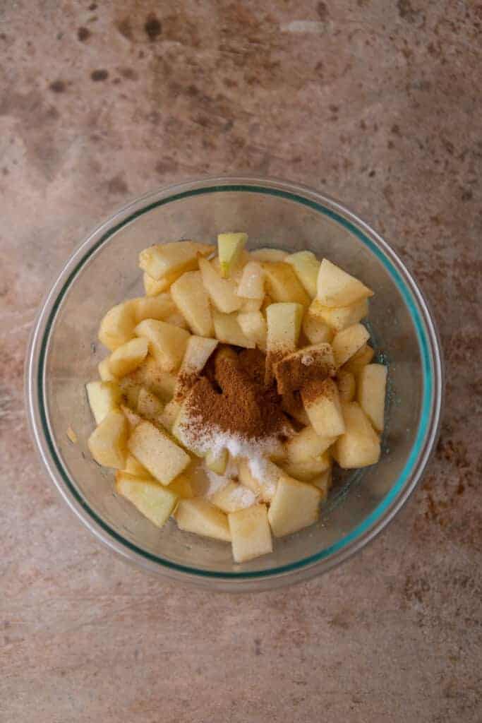 Pommes coupées dans un bol avec cannelle et sucre