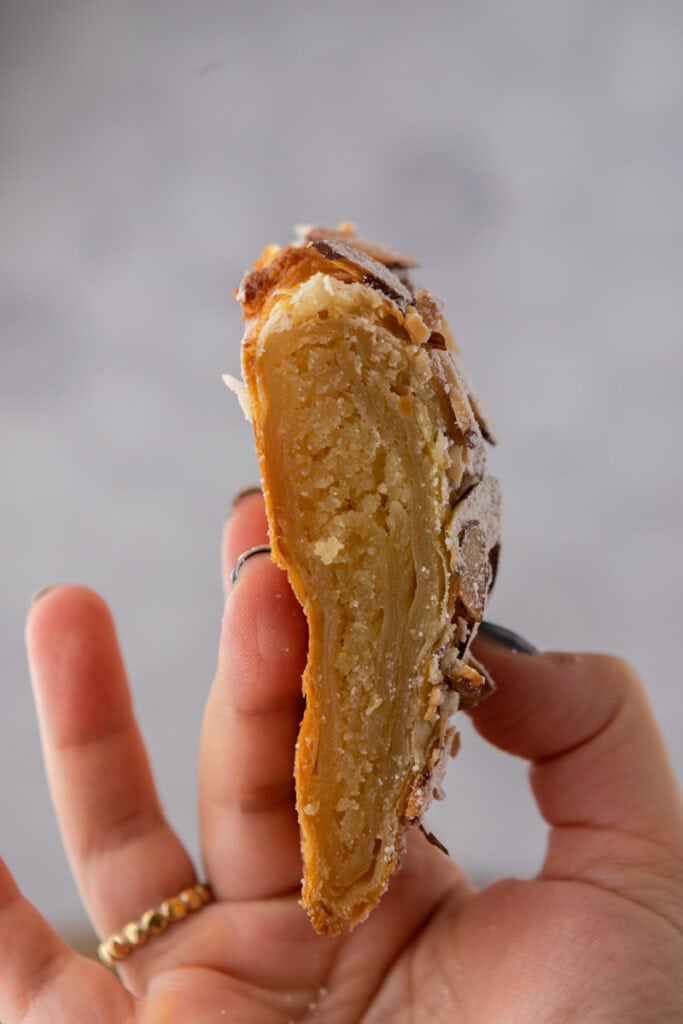 morceau de croissant aux amandes tressé présenté dans une main